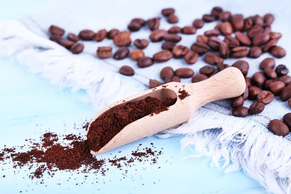 Wooden scoop with ground coffee and beans on jeans material, on blue background — Stock Photo, Image