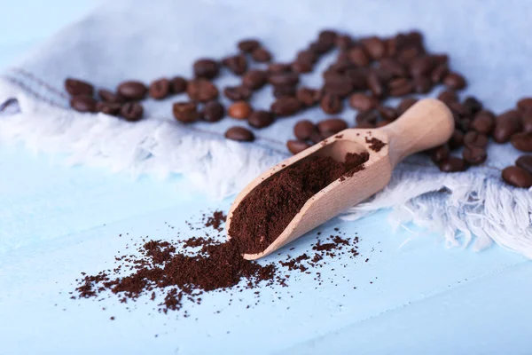 Wooden scoop with ground coffee and beans on jeans material, on blue background — Stock Photo, Image