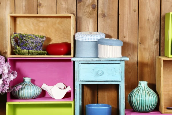 Hermosos estantes coloridos con diferentes objetos relacionados con el hogar en fondo de pared de madera — Foto de Stock