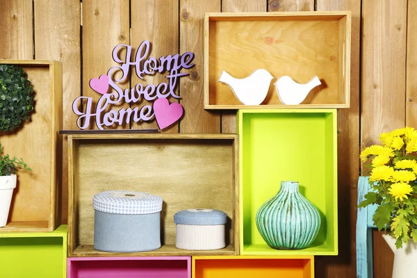 Beautiful colorful shelves with different home related objects on wooden wall background — Stock Photo, Image