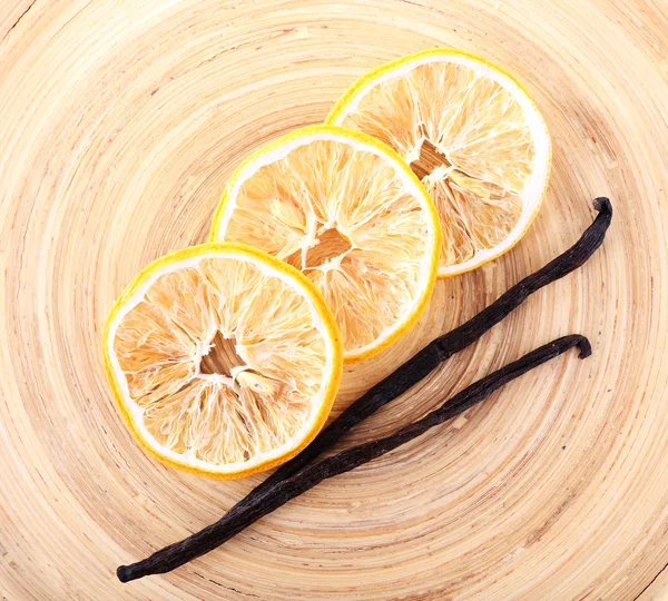 Dried slices of lemon with vanilla beans on wooden background — Stock Photo, Image