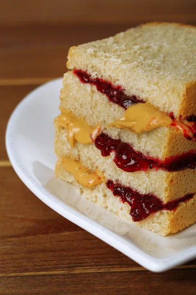 Lekkere sandwich met jam en pindakaas, op houten tafel — Stockfoto