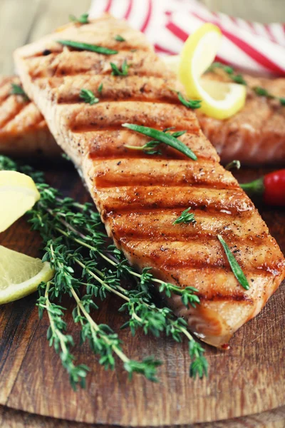 Gegrilde zalm op snijplank op houten achtergrond — Stockfoto