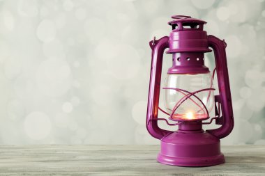Oil lamp on wooden surface and blurred background clipart