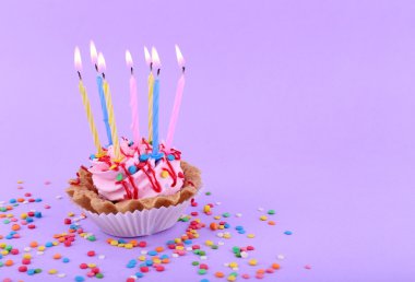Doğum günü kek mumlar ve mor arka plan üzerinde renkli parıldıyor