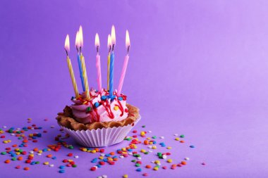 Doğum günü kek mumlar ve mor arka plan üzerinde renkli parıldıyor