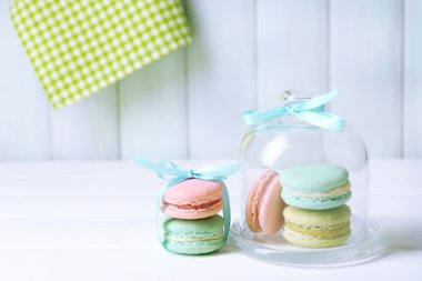 Gentle colorful macaroons in glass bell jar on color wooden table background
