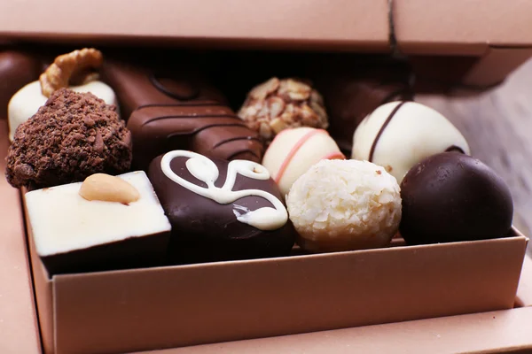 Caja llena de chocolates sobre fondo rústico de madera — Foto de Stock