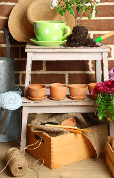 Flores em caixa de madeira, vasos e ferramentas de jardim no fundo de tijolos. Conceito de plantação de flores — Fotografia de Stock