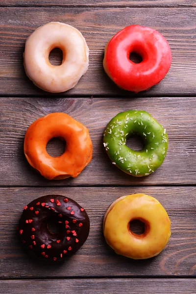 Deliciosos donuts com esmalte em fundo de madeira — Fotografia de Stock