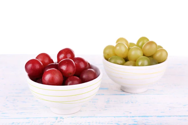 Twee kommen van groene en rode druiven op houten oppervlak kleur geïsoleerd op witte achtergrond — Stockfoto