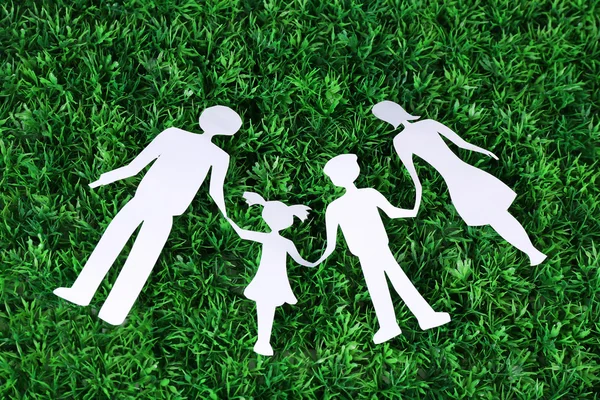 Paper family lying on green grass background — Stock Photo, Image