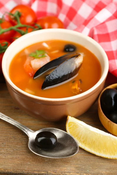 Sopa saborosa com camarões, mexilhões, tomates e azeitonas pretas em tigela sobre fundo de madeira — Fotografia de Stock