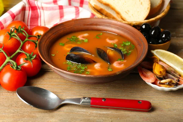 Sopa saborosa com camarões, mexilhões, tomates e azeitonas pretas em tigela sobre fundo de madeira — Fotografia de Stock