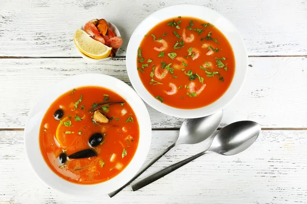 Tasty soups with  sea food in bowls on wooden background — Stock Photo, Image