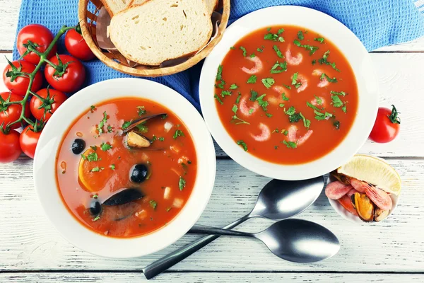 Sopas saborosas com comida do mar em tigelas em fundo de madeira — Fotografia de Stock