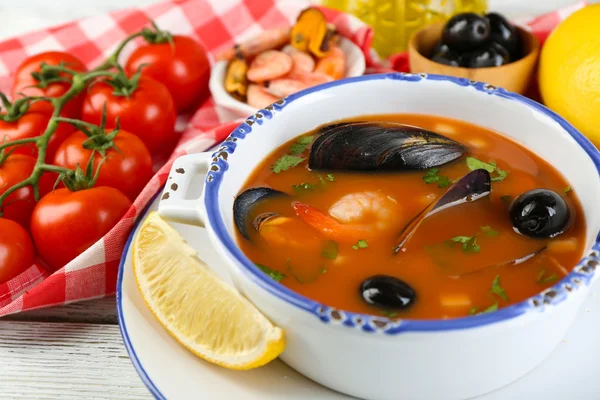 Sopa saborosa com camarões, mexilhões, tomates e azeitonas pretas em tigela sobre fundo de madeira — Fotografia de Stock