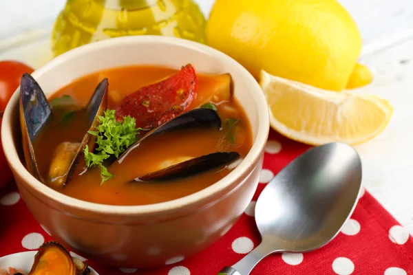 Tasty soup with shrimps, mussels, tomatoes and black olives in bowl on wooden background — Stock Photo, Image