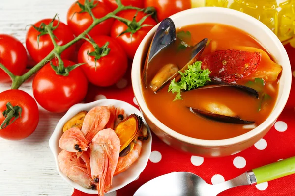 Tasty soup with shrimps, mussels, tomatoes and black olives in bowl on wooden background — Stock Photo, Image