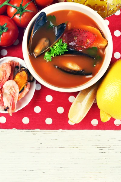 Tasty soup with shrimps, mussels, tomatoes and black olives in bowl on wooden background — Stock Photo, Image