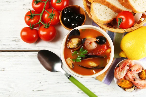 Смачний суп з креветками, мідіями, помідорами та чорними оливками в мисці на дерев'яному фоні — стокове фото