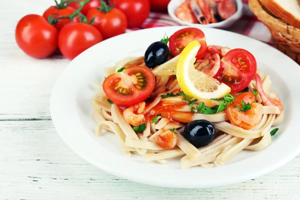 맛 있는 파스타와 새우, 블랙 올리브와 나무 배경에 접시에 토마토 소스 — 스톡 사진