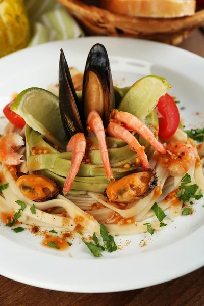 Tasty pasta with shrimps, mussels, tomatoes on plate on wooden background — Stock Photo, Image