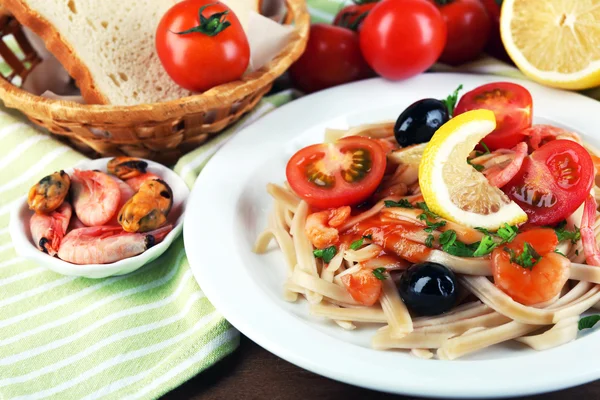 Вкусная паста с креветками, мидиями, черными оливками и томатным соусом на деревянном фоне — стоковое фото