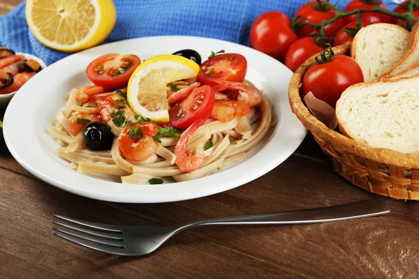 Pasta saporita con gamberetti, cozze, olive nere e salsa di pomodoro su fondo di legno — Foto Stock