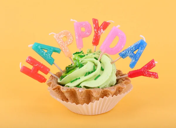 Cake met birthday kaarsen op oranje achtergrond — Stockfoto