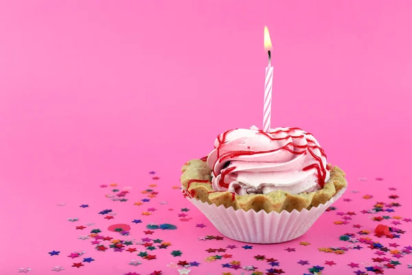 Tarta de cumpleaños con vela y estrellas de colores sobre fondo rosa — Foto de Stock