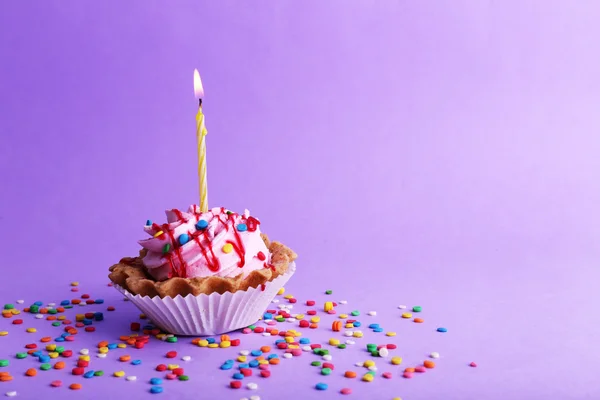 Geburtstagstorte mit Kerze und bunten Funkeln auf lila Hintergrund — Stockfoto