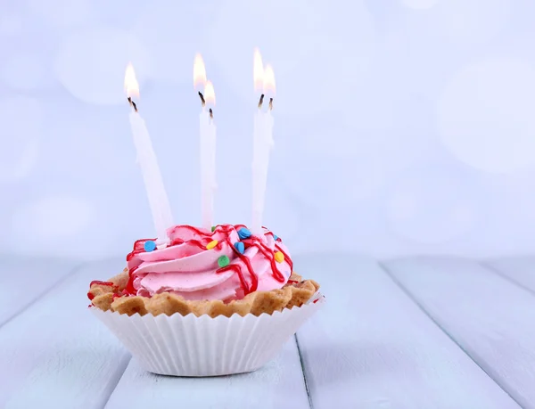 Κύπελλο κέικ γενεθλίων με κεριά και αστράφτει στο ξύλινο τραπέζι χρώμα και ανοιχτό φόντο — Φωτογραφία Αρχείου