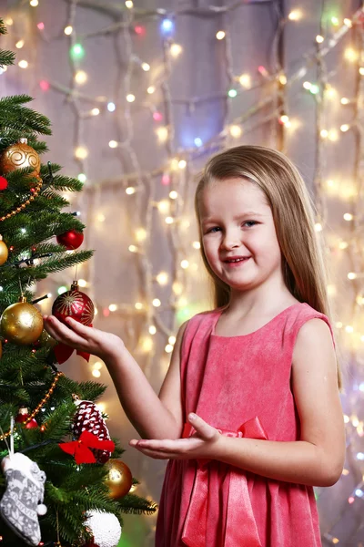 Little girl decorating Christmas tree on bright background — Stock Photo, Image