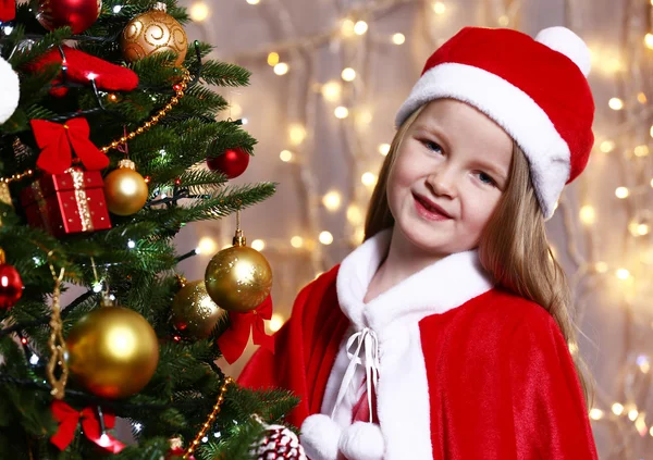 Little girl near Christmas tree on bright background — 图库照片