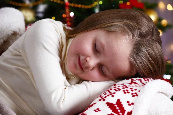 Little girl sleeping on Christmas tree background — Stok fotoğraf