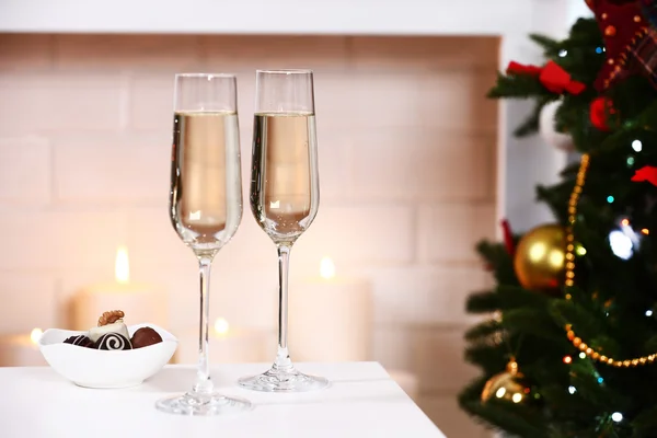 Two glass with champagne with bowl of chocolates on table on Fireplace background — 스톡 사진