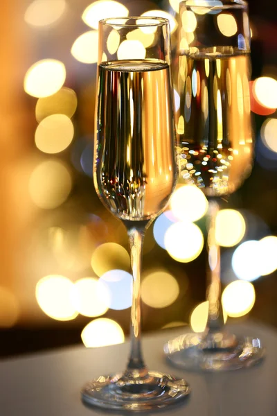 Dos copas con champán en la mesa sobre fondo brillante —  Fotos de Stock