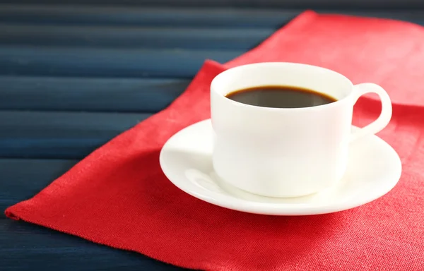 Cup of coffee on red napkin color wooden background — Stock Photo, Image