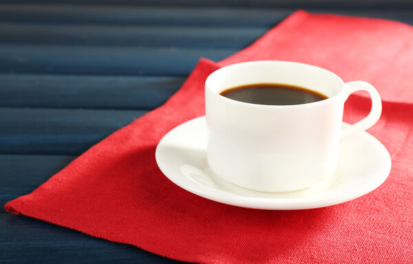 Cup of coffee on red napkin color wooden background