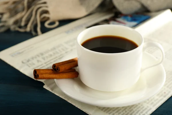 Taza de café con periódico, cuadros y canela sobre fondo de madera de color — Foto de Stock