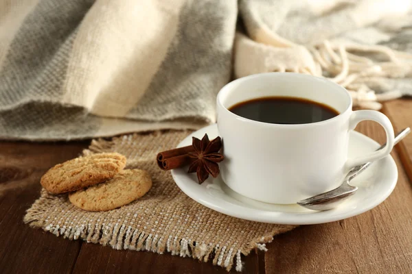 Xícara de café com biscoitos, anis estrelado e canela em pano de serapilheira em fundo de mesa de madeira — Fotografia de Stock