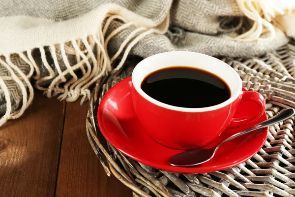 Cup of coffee on wicker stand near plaid on wooden table background — 图库照片
