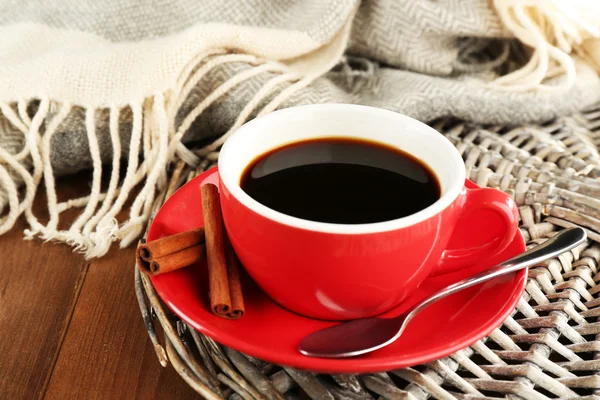 Cup of coffee on wicker stand near plaid on wooden table background — 图库照片