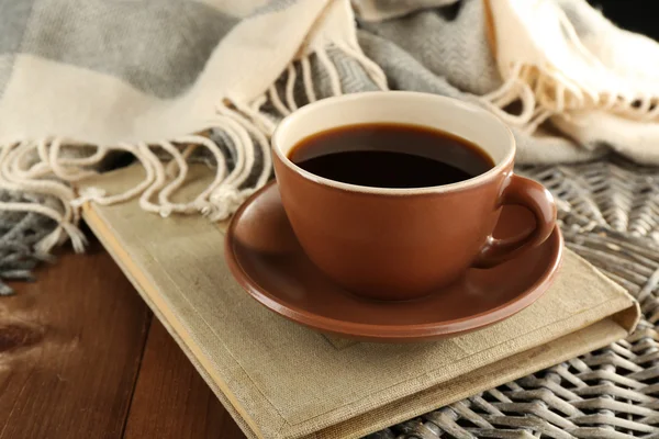 Cup of coffee on book near plaid on wooden table background — Zdjęcie stockowe
