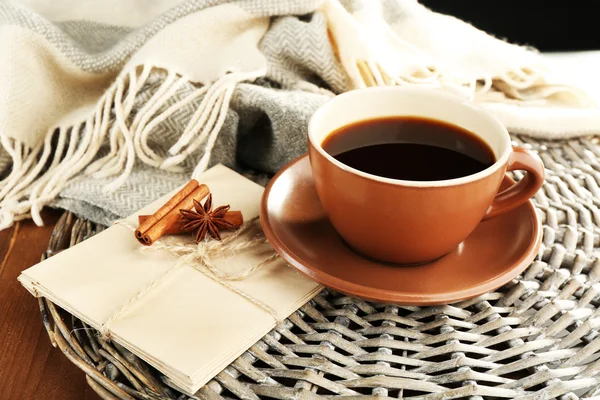 Tasse Kaffee mit Umschlägen auf Korbständer auf Holztischhintergrund — Stockfoto