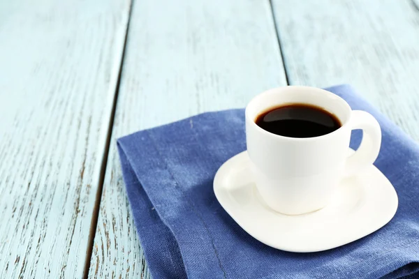 Cup of coffee on blue napkin on color wooden background — Stock Photo, Image