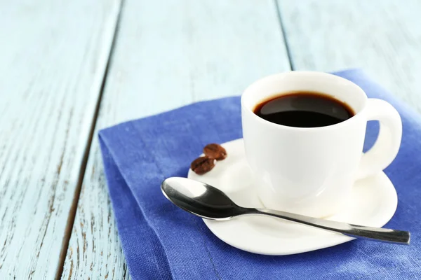 Cup of coffee on blue napkin on color wooden background — ストック写真