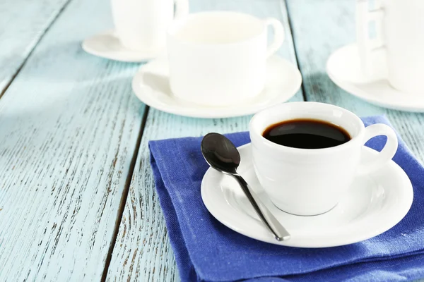 Cup of coffee with other cups on color wooden background — Φωτογραφία Αρχείου
