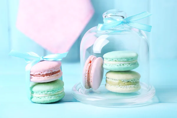 Macaroons coloridos suaves no frasco de sino de vidro na cor de fundo de mesa de madeira — Fotografia de Stock